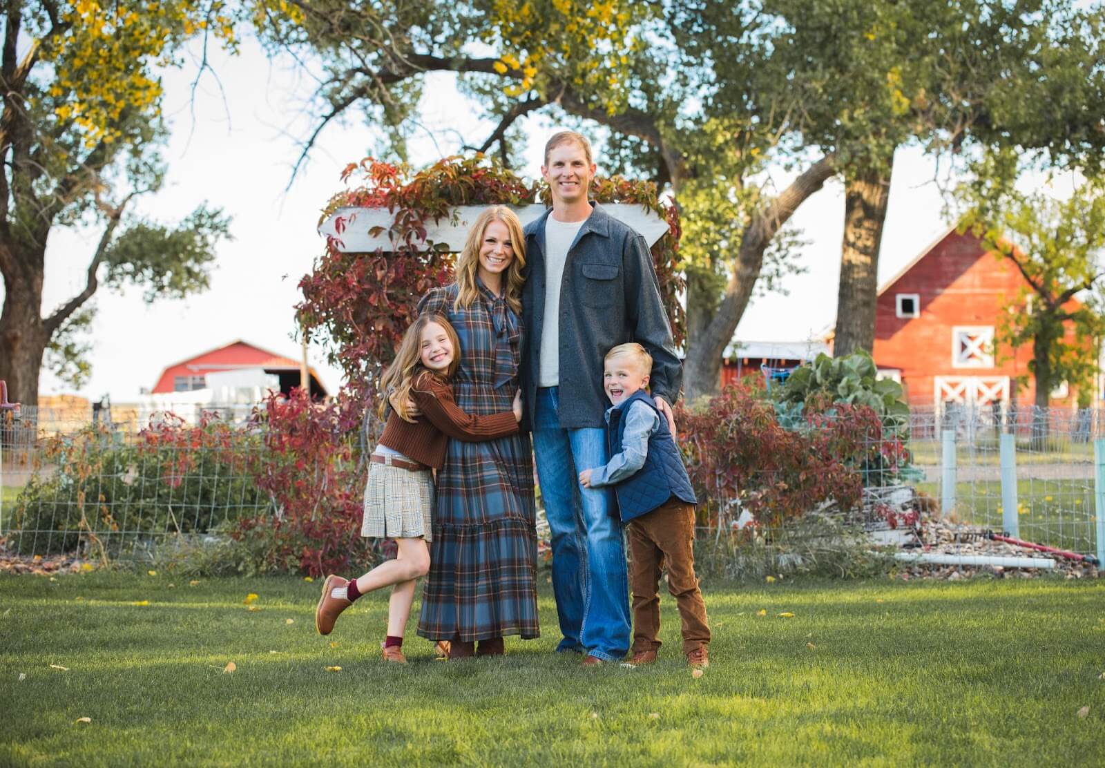 Family posing in front of red barn.